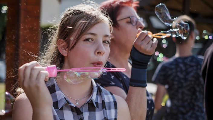 Eine Jugendliche und eine pädagogische Fachkraft pusten Seifenblasen.